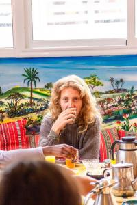 Una donna seduta a tavola che mangia. di Happy Surf Hostel a Taghazout