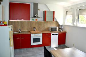 una cocina con armarios rojos y una estufa blanca en Ferienwohnung Waldblick Bückeburg, en Bückeburg