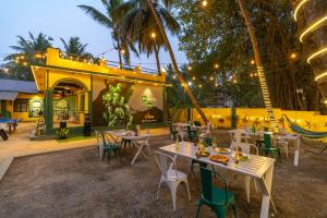 un restaurante con mesas y sillas frente a un edificio en Whoopers Hostel Anjuna, Goa en Anjuna