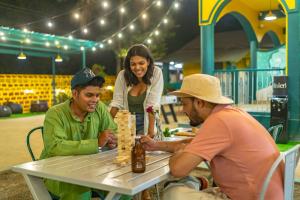 two men and a woman playing a game at a table at Whoopers Hostel Anjuna, Goa in Anjuna