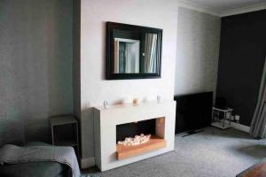 een woonkamer met een open haard en een spiegel bij SL Luxury 3 Bedroom Home in Holly Lane