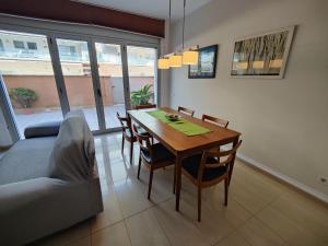 Badalona Beach Apartment في بادالونا: غرفة طعام مع طاولة وكراسي وأريكة