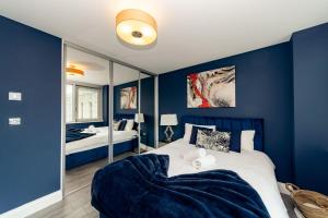 niebieska sypialnia z łóżkiem i lustrem w obiekcie Spacious Morden Apartment I Next to Brighton Beach w Brighton and Hove