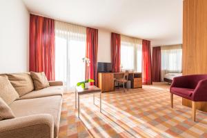 a living room with a couch and a desk in a room at Hotel Tubris Garnì Campo Tures in Campo Tures