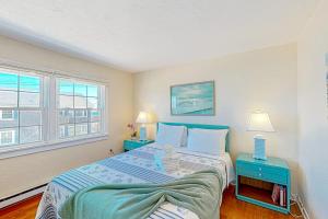 1 dormitorio con 1 cama grande y 2 mesas azules en Bay Colony Vista, en Provincetown