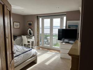 a bedroom with a bed and a television and a balcony at The View in Tynemouth