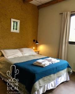 a bedroom with a bed with blue sheets and a window at Color Local Cabañas in San Javier +31 photos