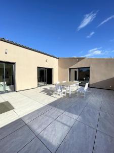 a patio with a table and chairs on a building at Villa 400m2 piscine intérieure très calme in Agde