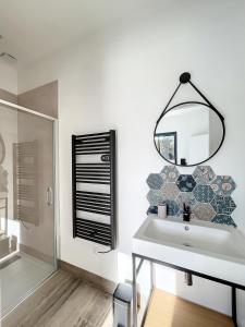 a bathroom with a sink and a shower and a mirror at Villa 400m2 piscine intérieure très calme in Agde