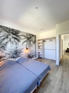 a bedroom with a blue bed with a palm tree mural at Villa 400m2 piscine intérieure très calme in Agde