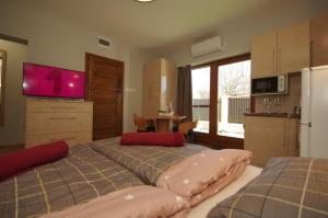 a bedroom with two beds and a kitchen with a refrigerator at Paradiso Apartmanház in Gyula