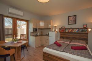 a bedroom with a bed and a table and a kitchen at Paradiso Apartmanház in Gyula