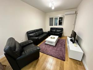 a living room with black leather furniture and a tv at Apartman VT 2 Central point in Podgorica
