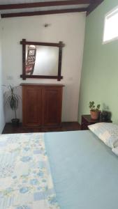a bedroom with a bed and a dresser and a mirror at Chalé Claudio Rambo in Ilhabela