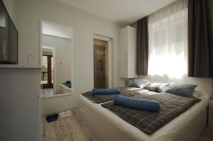 1 dormitorio con cama con almohadas azules y espejo en Paradiso Apartmanház, en Gyula