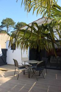 een patio met een tafel en stoelen en een palmboom bij Maisonnette 2 pièces 100m de la plage de la Clère in Le Grand Vieil