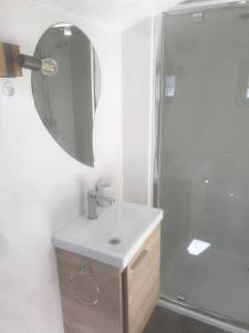 een witte badkamer met een wastafel en een spiegel bij Maisonnette 2 pièces 100m de la plage de la Clère in Le Grand Vieil