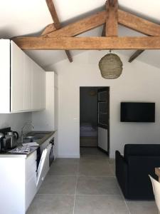 een keuken met witte kasten en een zwarte bank bij Maisonnette 2 pièces 100m de la plage de la Clère in Le Grand Vieil