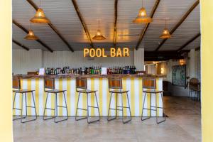 un bar con taburetes en una habitación con bar junto a la piscina en Café Jeri Hotel en Jericoacoara