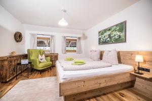 a bedroom with a bed and a green chair at Oberhaslachhof in Reith im Alpbachtal