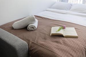 a bed with a towel and a book and a flower at River To The City - Studio 7b Apartment in Vilnius