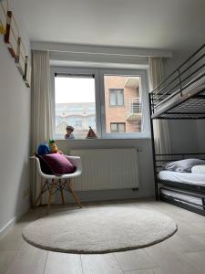 a bedroom with bunk beds and a chair and a window at Blankeduyn Koksijde in Koksijde