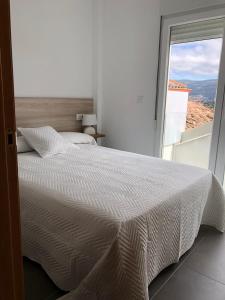 a bedroom with a white bed and a large window at Apartamentos Corcubión in Corcubión