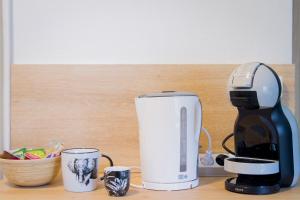 a coffee maker and two cups on a counter at Le TropiCool in Chalezeule