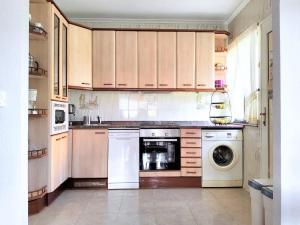 cocina con armarios de madera, lavadora y secadora en Casa la Juncara, en Guarnizo