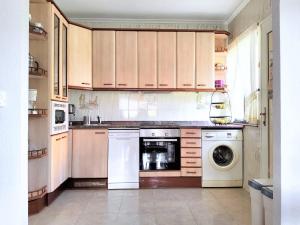 a kitchen with wooden cabinets and a washer and dryer at Casa la Juncara in Guarnizo