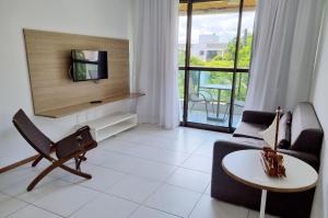 sala de estar con TV, sofá y mesa en ILOA J - Apartamento Família, en Barra de São Miguel