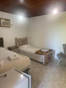 a room with two beds and a tv and a chair at Hotel Fazenda VCP in Silva Jardim