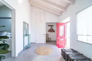 una porta rossa in una stanza bianca con tavolo di Peaceful, spacious & stylish, a real home! a Budens
