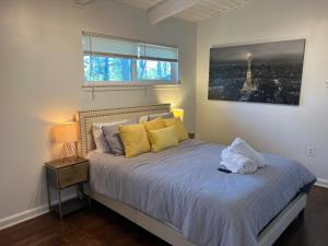a bedroom with a bed with yellow pillows and a window at Recently renovated Haven in Brookhaven. in Atlanta