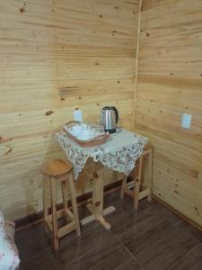 a small table in a wooden room with a tea kettle at cabanas paisagem da serra in Urubici