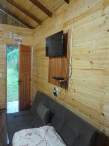 a room with a couch and a tv on a wooden wall at cabanas paisagem da serra in Urubici