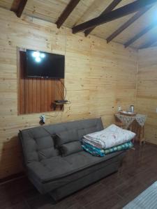 a living room with a couch and a flat screen tv at cabanas paisagem da serra in Urubici