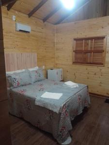 a bedroom with a bed in a wooden room at cabanas paisagem da serra in Urubici