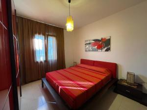 ein rotes Bett in einem Zimmer mit Fenster in der Unterkunft Appartamenti Abbaidda 2 in Valledoria