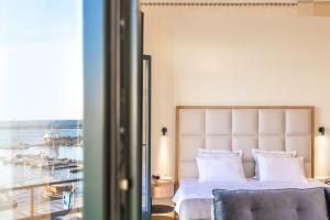 a bedroom with a bed and a view of a harbor at EPICURE SUITES in Kavala