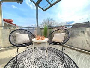 two chairs and a table on a balcony at RONI APARTMENTS -111qm Luxury Loft -Near Center and Clinics -Netflix -Terrace -Close to Thermal Spa in Bad Aibling