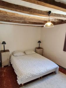een slaapkamer met een wit bed en 2 nachtkastjes bij Le Coeur de Fresnay in Fresnay-sur-Sarthe