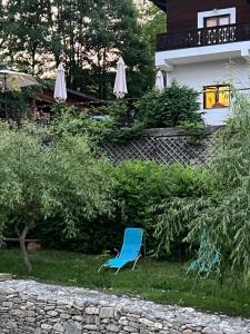 a blue chair sitting in the grass in front of a house at Pension Valentina in Mănăstirea Humorului