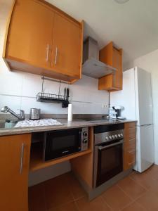 a kitchen with wooden cabinets and a black oven at Apartamento en el Grao de Gandía in Gandía