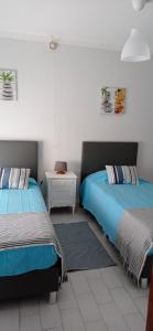 Duas camas sentadas uma ao lado da outra num quarto em Alojamento Dona Inês de Castro em Atouguia da Baleia