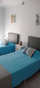 a bedroom with two beds with blue sheets at Alojamento Dona Inês de Castro in Atouguia da Baleia