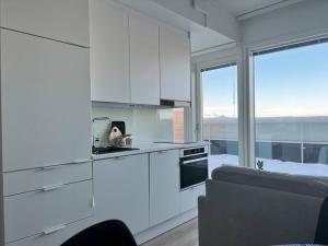 a kitchen with white cabinets and a large window at Modern Penthouse Studio with Private Terrace in Rovaniemi