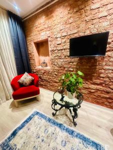uma sala de estar com uma cadeira vermelha e uma televisão numa parede de tijolos em Taksim studio em Istambul
