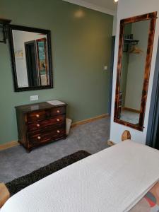 a bedroom with a bed and a dresser and a mirror at Pensalda Guest House in Newquay