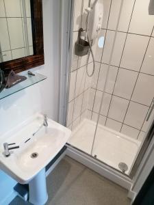 baño blanco con ducha y lavamanos en Pensalda Guest House en Newquay